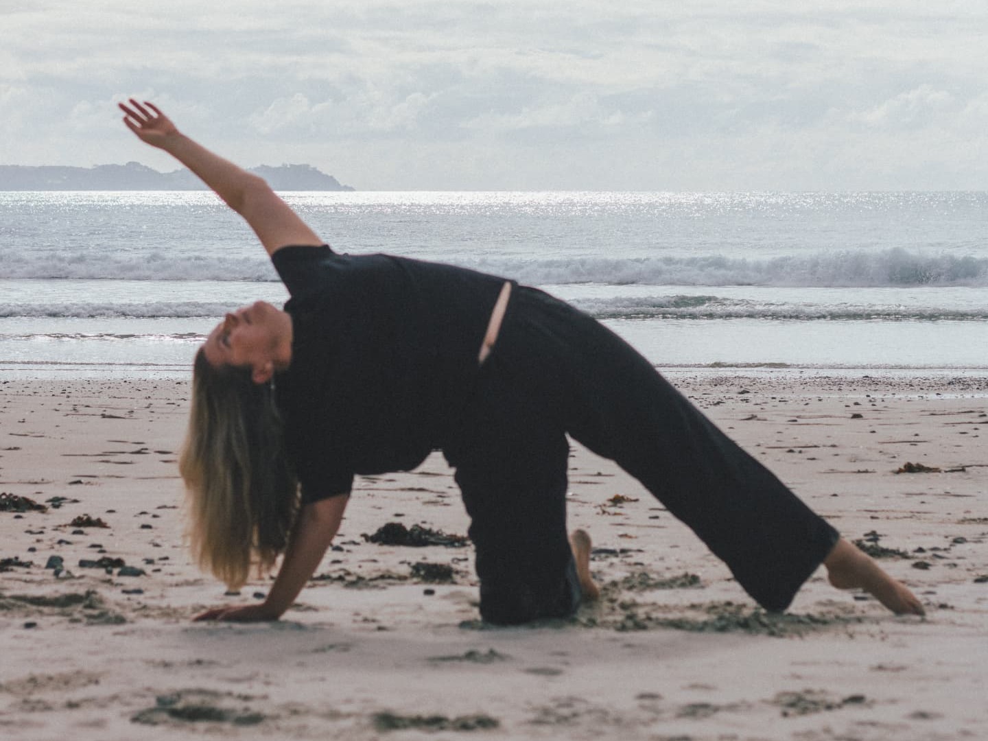 Saskia practising a backbend yoga pose on the beach